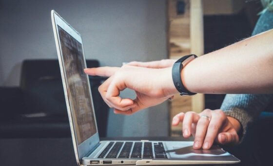 Hai người trao đổi trước máy tính xách tay tại bàn làm việc, ảnh minh họa